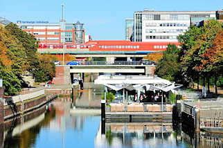 0758 Mittelkanal in Hamburg Hammerbrook - auf einem Ponton ist ein Restaurant eingerichtet - in der S-Bahnstation Hammerbrook fährt ein Zug ein.