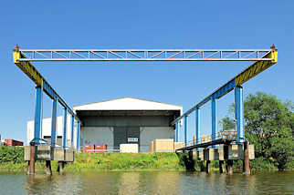 5698 Krananlage über dem Wasser des Moorfleeter Kanals im Hamburger Stadtteil Billbrook - Lagerhalle am Ufer des Kanals.