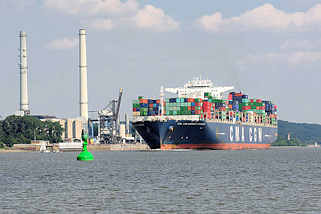 7081 Der Containerfrachter CMA CGM Amerigo Vespucci auf der Elbe vor Wedel - am Ufer die Schornsteine und das Heizkraftwerk Wedel. Die Amerigo Vespucci hat eine Länge von 365 m und kann 13830 TEU Container transportieren.
