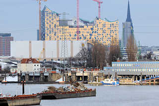2727 Blick über den Travehafen in Hamburg Steinwerder - beladene Schuten liegen an Dalben - lks. die Ellerholzschleuse, rechts Gebäude der Wasserschutzpolizei; im Hintergrund Baustelle der Elbphilharmonie und Turm der St. Nikolaikirche.