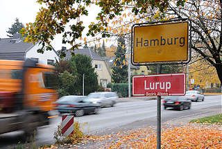 1523 Hamburger Stadtgrenze, gelbes Grenzschild und rotes Stadtteilschild, Autoverkehr mit schnell fahrenden Autos.