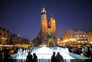 0115 Marktplatz mit Springbrunnen am Abend - Nachaufnahme, beleuchtete Trme des Krakauer Wahrzeichens die Marienkirche.