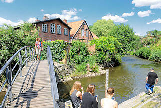 9312 Fussgängerbrücke über die Trave - Jugendliche sitzen am Flussufer in Bad Oldesloe, Kreis Stormarn.