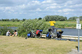 7233 Fahrradtour - Rast an der Elbe bei Bleckede; hoch bepackte Fahrräder / Fahrradtaschen - Picknick am Wasser.