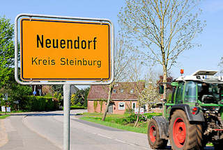 1461 Ortsschild Neuendorf Kreis Steinburg; Trecker / Taktor auf der Strasse. 